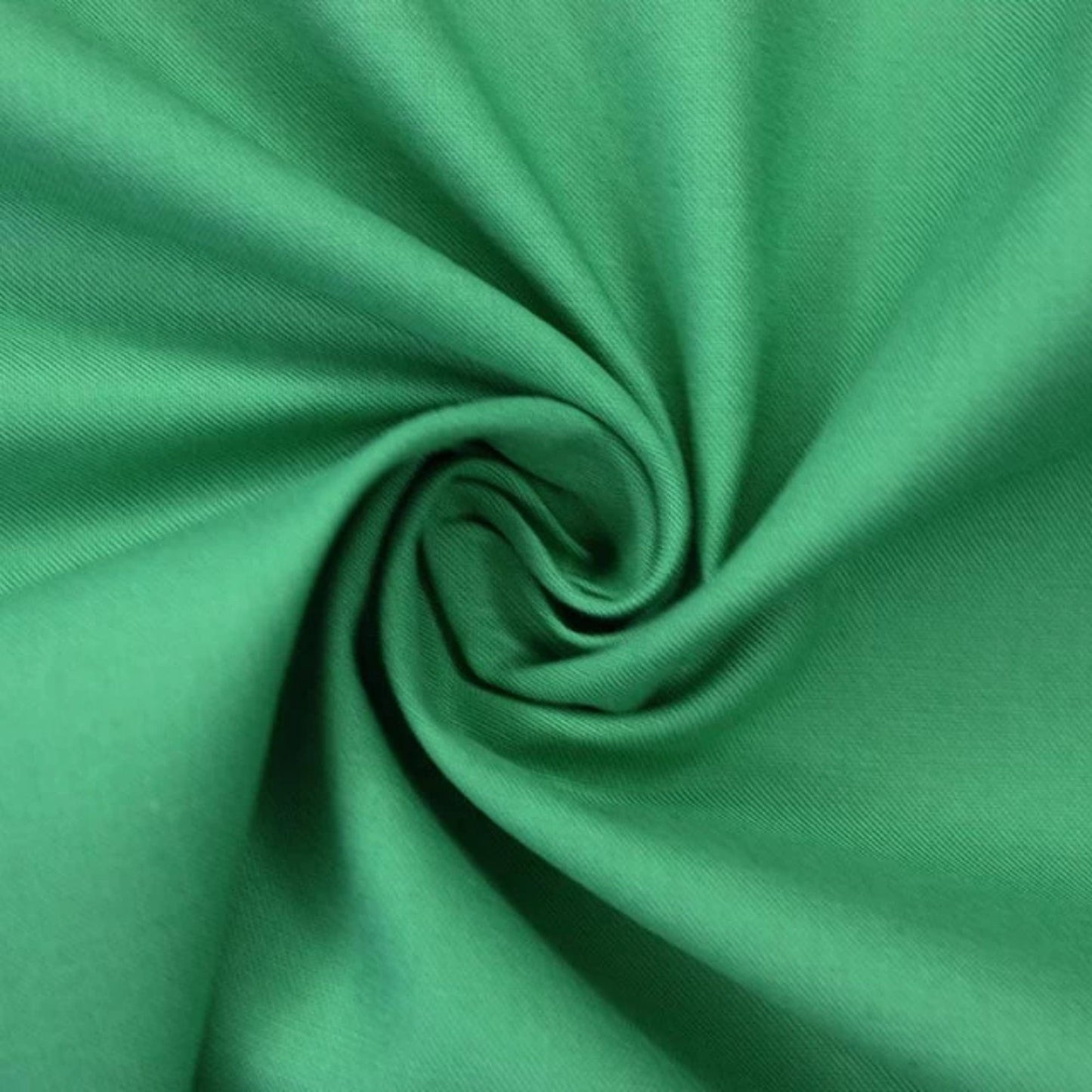 A close-up of bright green fabric arranged in a spiral swirl, showing the material texture and drape.