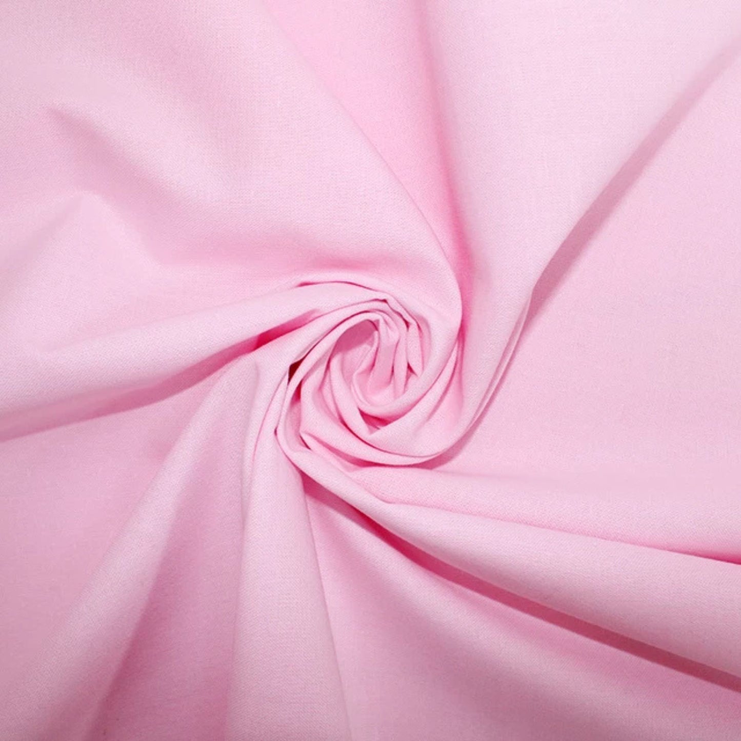 A close-up of light pink fabric arranged in a spiral swirl, showing the material's texture and color.