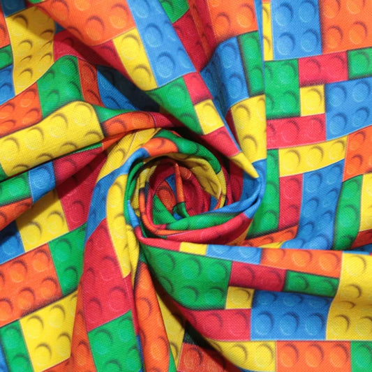A close-up of colorful fabric printed with a repeating pattern of toy building-block squares in red, orange, yellow, green, and blue, arranged in a spiral drape.