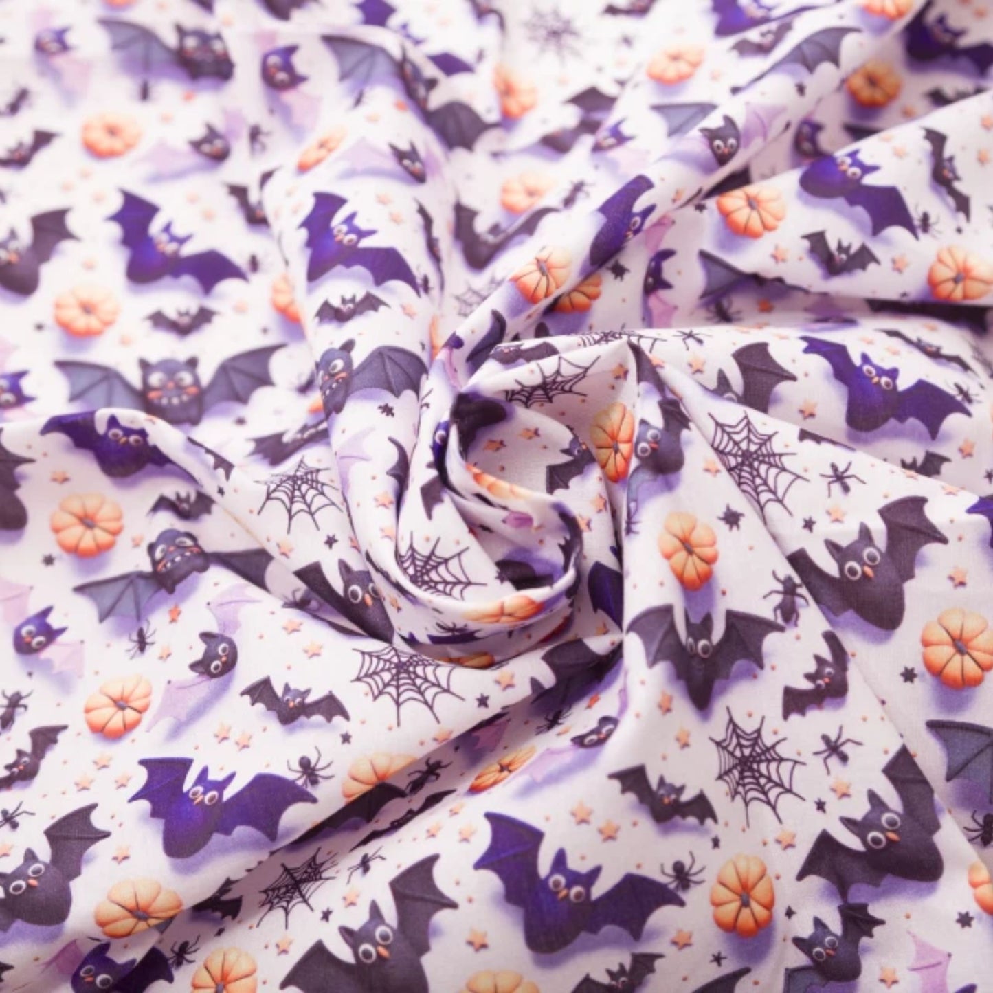 Halloween-themed fabric with a repeating pattern of purple bats, orange pumpkins, black spiderwebs, and small stars on a white background, styled in a central swirl.