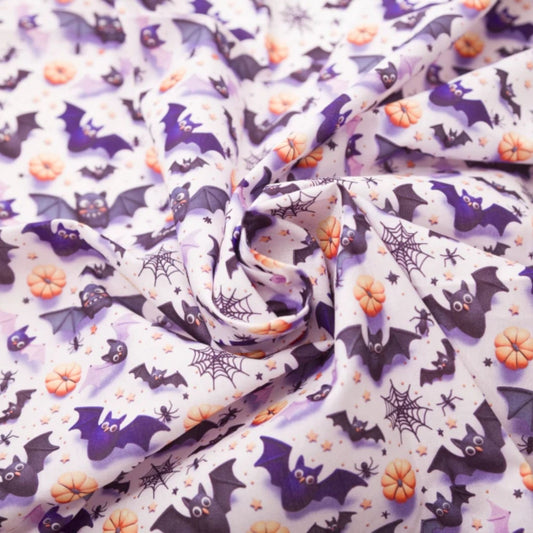 Halloween-themed fabric with a repeating pattern of purple bats, orange pumpkins, black spiderwebs, and small stars on a white background, styled in a central swirl.