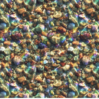 A close-up texture of small multicolored fabric pebbles and stones in shallow water, with iridescent rainbow reflections across the surface.